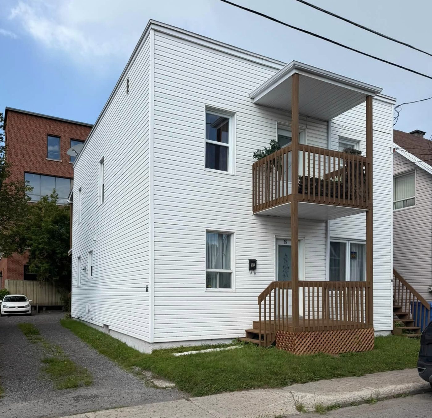 Duplex rénové avec revêtement blanc et galeries en bois
